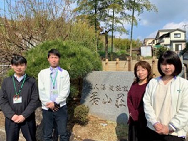 四人のスタッフと看板 看板 介護施設の前で四人のスタッフが並んでいます。チームワークの良さが伝わります。