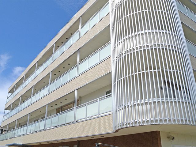 三階建て建物の外観 外観 明るい空とともに、三階建ての建物は清潔感があります。大きな窓が特徴です。