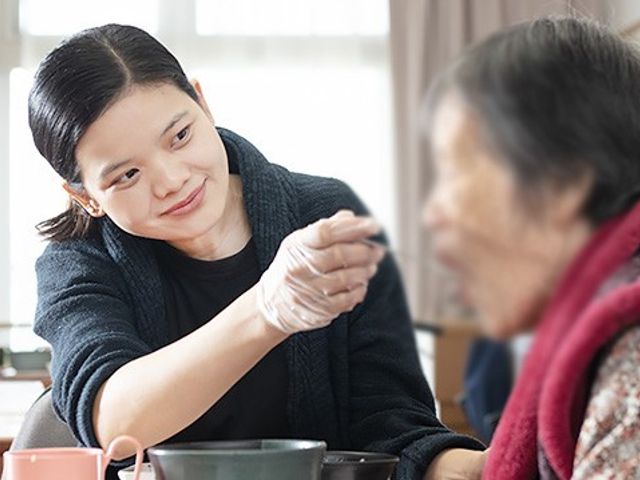 食事支援の様子 ダイニングルーム 広々とした空間で、スタッフが丁寧に食事のサポートを行っています。温かい雰囲気の場所です。