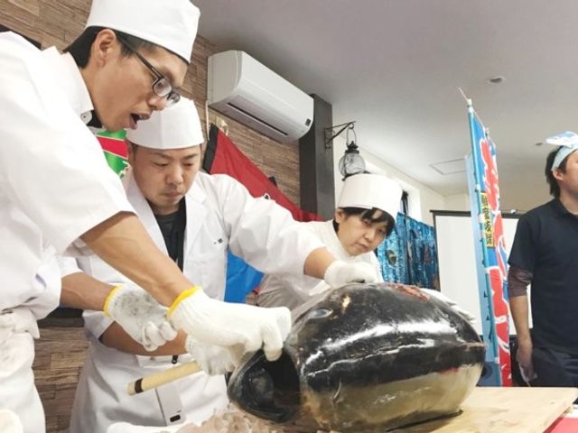 共有スペースでの料理イベント ダイニングルーム 料理スタッフが巨大な魚をさばいており、楽しい雰囲気の中での特別イベントが催されています。
