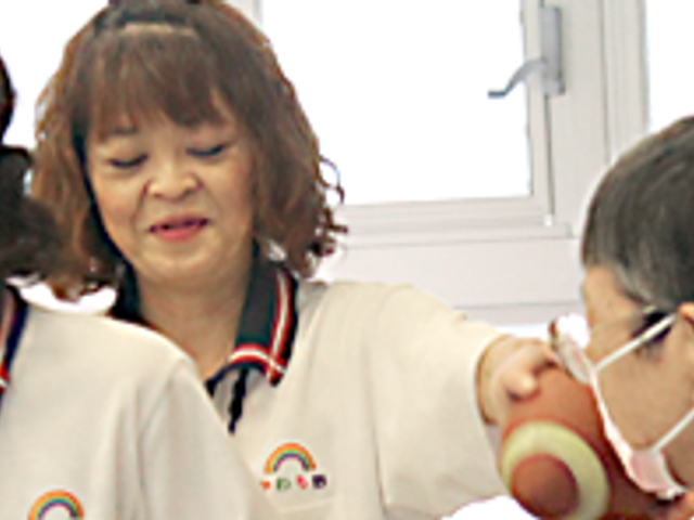 楽しそうな会話の居室 居室 スタッフと利用者が談笑しながら楽しいひと時を過ごしている様子です。和やかな雰囲気が広がっています。