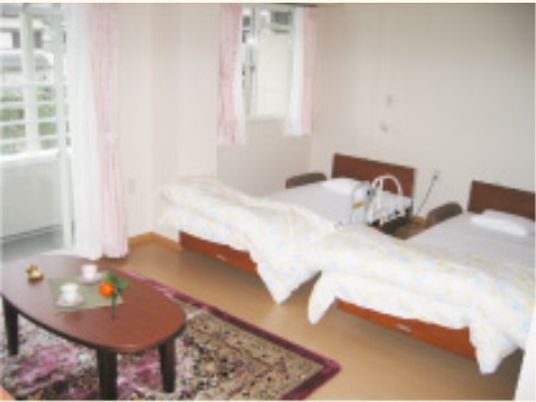 テーブルや介護用ベッドが２つ置かれた居室。ご夫婦や兄弟などで入居することが可能な、広い部屋となっている。