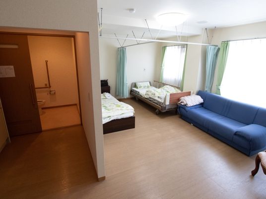 施設の写真 二人用の生活のための居室。居室内にはトイレが備え付けられており、ベッドの部分を備えつけのカーテンで区切ることも可能である。