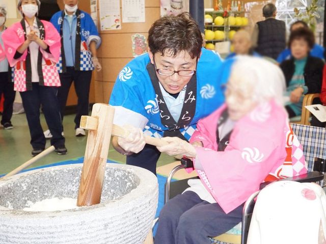 楽しいイベント 多目的室 スタッフが利用者と一緒に楽しい行事を行っています。互いに協力して餅つきを楽しむ様子です。