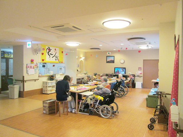明るい活動空間 デイルーム ゆったりとした空間で日々の活動を楽しむ姿が見られます。明るく開放感のある場所で、笑顔で過ごす方々がいます。