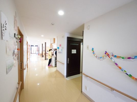 広々とした通路がある。通路には手すりが設置されている。通路の途中には居室に通じる扉がある。通路奥にはリビングがある。