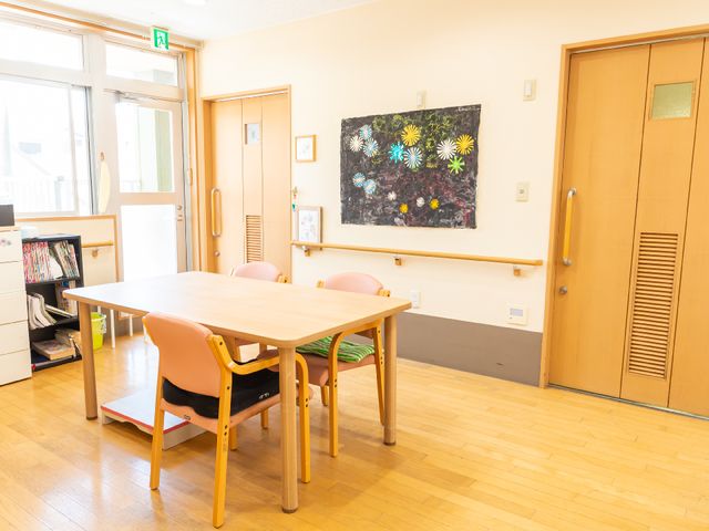 明るい共有スペース 共有スペース 床の木目と絵画が印象的な休息スペースです。柔らかな光が差し込む落ち着いた雰囲気で、リラックスして過ごせます。