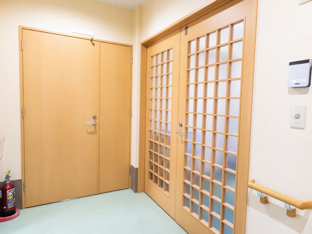 廊下に面した二つの扉 廊下 手すり付きの廊下には二つの扉があり、安全に配慮された設計です。扉の一つは格子窓で、明るさを提供しています。