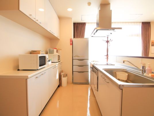 フラットな床のキッチンは、アイランド型のシンクと大型冷蔵庫、電子レンジなどが備えつけられており、白色を基調にまとめられている。