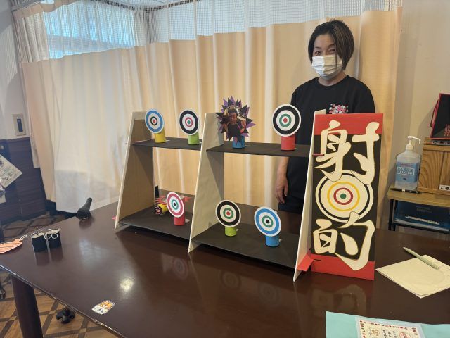 射的ゲームコーナー スタッフイメージ 職員の方が射的ゲームを準備しています。イベントを通して楽しい雰囲気作りを大切にされています。