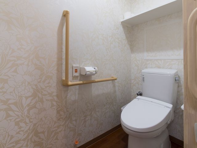 清潔感あるトイレ空間 トイレ 手すりを備えたトイレ空間で、安全かつ自立した日常生活をサポートしています。壁の装飾も柔らかな雰囲気を演出し、落ち着いた時間をお過ごしいただける設計です。