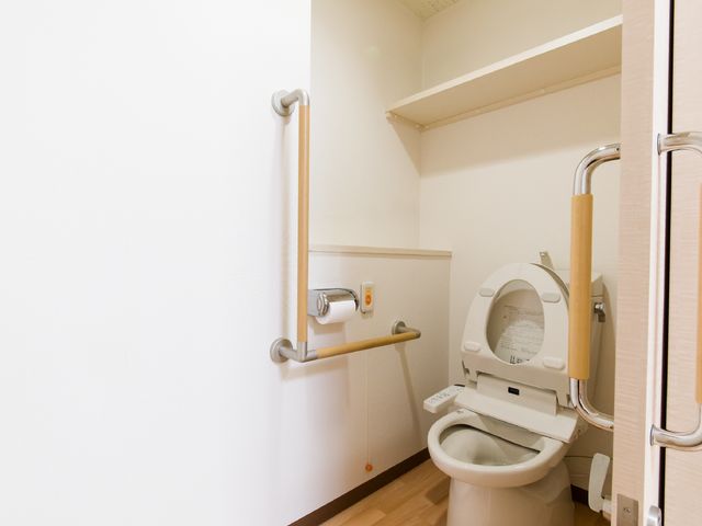 バリアフリー対応のトイレ 広いトイレ 手すりが設置された清潔感のある空間です。利用者の安全を考えた設計になっています。