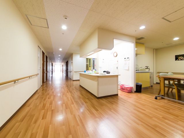 明るい廊下とリビングエリア スタッフルーム 廊下は広く、ゆったりとした作りです。手すりや床も清潔感があり、明るい雰囲気を保っています。