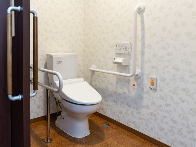 バリアフリー設計のトイレ トイレ 手すりが設置された安全なトイレ空間です。緊急時に備えた呼び出しボタンも完備しており、安心してご利用いただけます。