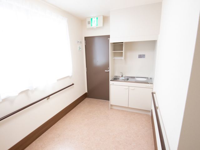 清潔な居室の一角 キッチン この居室は洗練されたデザインで、日々の生活に必要な設備が整っています。快適な環境でケアを提供できる空間です。
