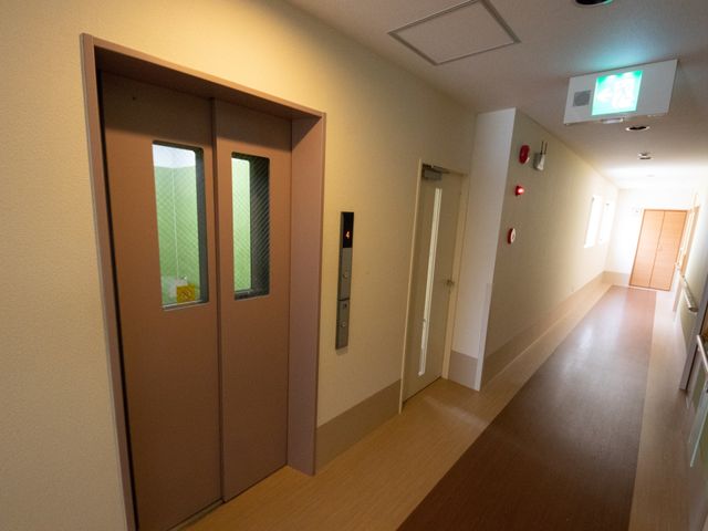 清潔感のある廊下 エレベーター 手すりが備わった落ち着いた雰囲気の廊下です。通路も広く、皆様の快適な移動をサポートしています。