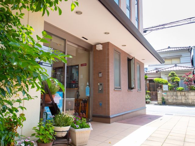明るいエントランスの外観 玄関 花々で彩られたエントランスが迎える、安らぎの空間です。来訪者にやさしい印象を与え、開放感ある設計となっています。