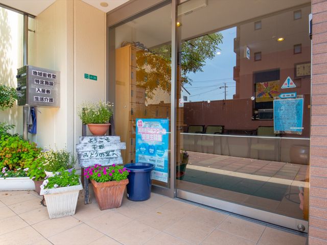 エントランス前の植物 玄関 ゆったりとした空間のエントランスは、明るく開放感があり、心地よい印象を与えます。さまざまな植物が訪れた人を温かく迎えてくれる様子が見受けられます。