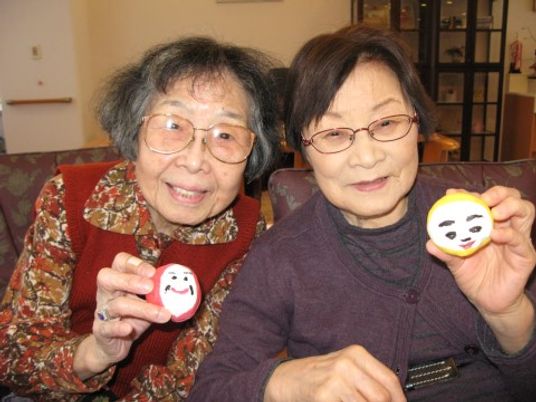 笑顔で手作り品を見せる利用者