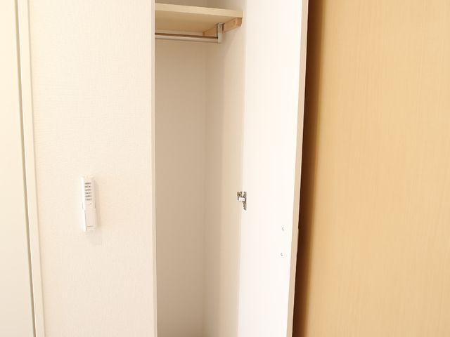 開いたクローゼットの扉 居室の造り付け収納クローゼット 収納スペースには可動棚が備えられ、利用者の必要に応じて調整が可能です。清潔感のあるデザインで、個人の趣味や衣類を整理しやすい造りになっています。