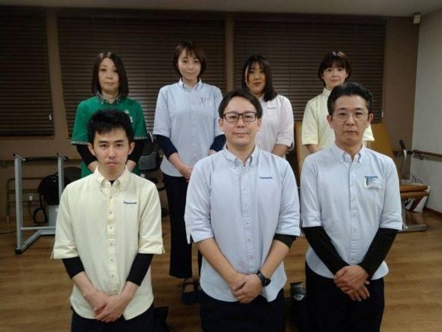 スタッフ集合の休憩室 休憩室   6人のスタッフが整列して立っており、落ち着いた雰囲気の休憩室です。就業を考える方は、職場の人の様子をイメージしやすいです。
