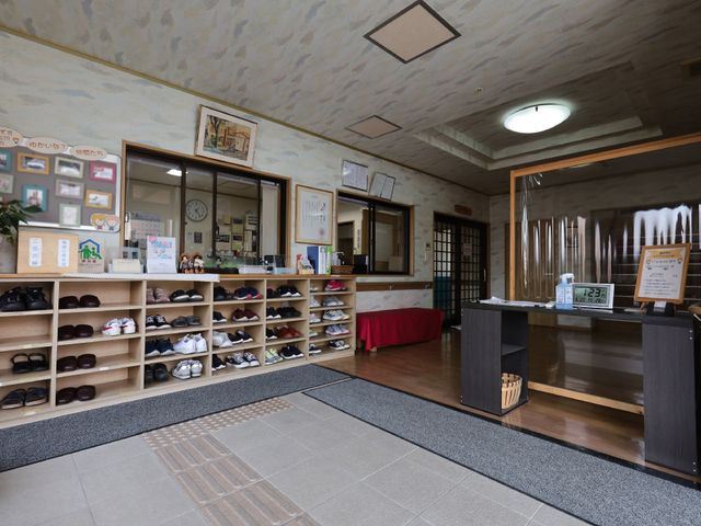 受付と靴棚のあるエントランス 玄関 温かみのある雰囲気の入口エリアです。来所される方々を迎える丁寧な受付や整理された靴棚が心地よい印象を与えます。
