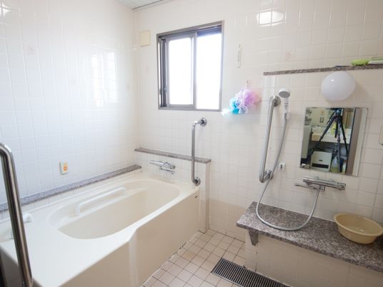 換気用の窓から日が入るので、浴室は明るく開放的になっている。手すりを多数設置してあるので安全に入浴することができる。