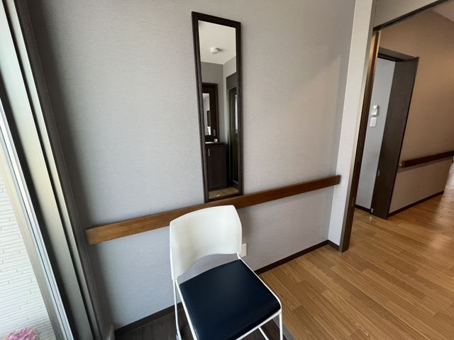 居室の手摺付き廊下 廊下 手すりが付いており、座って休憩できるイスが設置された廊下です。ゆったりとした間取りで、安全に移動できるよう配慮されています。