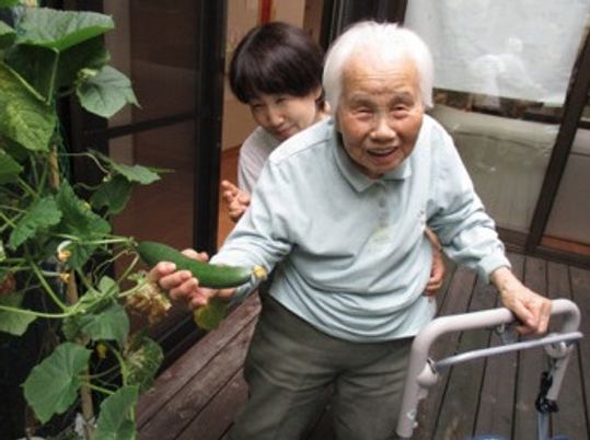 歩行器を使う高齢男性と介助者