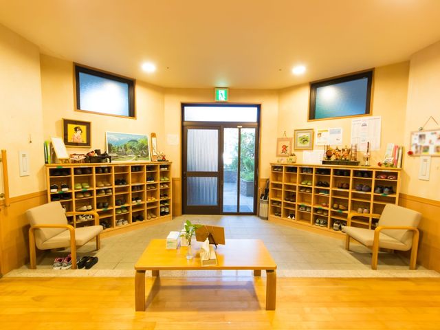 居心地の良いエントランス 玄関 暖かみのあるエントランスは、ゆったりとした椅子が配置され、落ち着いた時間を過ごせるようになっています。運動靴や履物が整然と収められた棚が、快適な環境づくりに一役買っています。