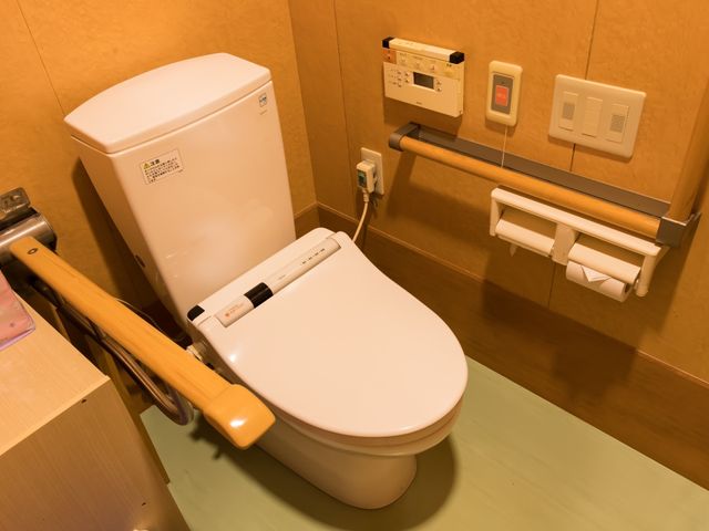 バリアフリートイレ設備 トイレ 手すり付きの快適なトイレ空間です。洗浄機能付き便座で、利用者の方々の快適性と安全性を配慮しています。