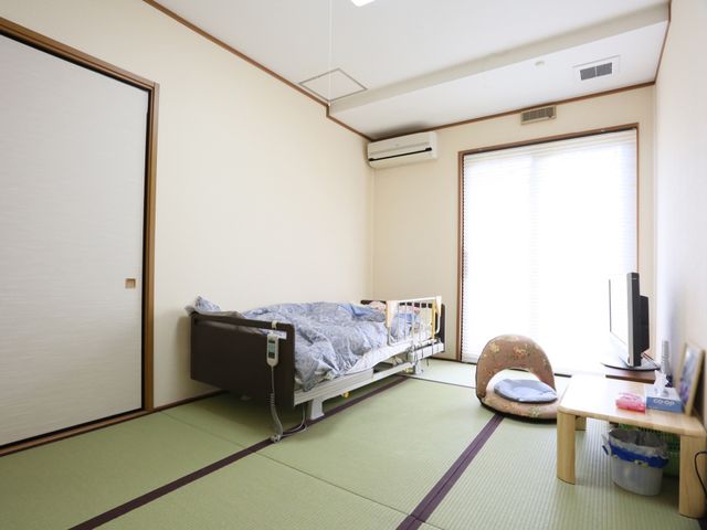 居室の和室の様子 居室 清潔感ある和の空間で、ゆったりとした時間を過ごすことができます。機能的なベッドと一人掛けの椅子が備わり、快適性が考慮されています。