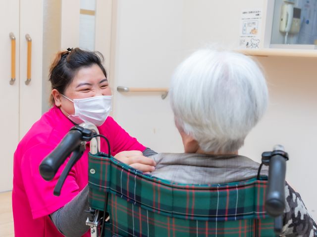 笑顔で会話するケアスタッフ スタッフ 笑顔で優しい対応をするスタッフの姿が、日々の心温まる支援の一端を表しています。お仕事は助け合いながら、利用者の方々に寄り添った時間を提供しています。
