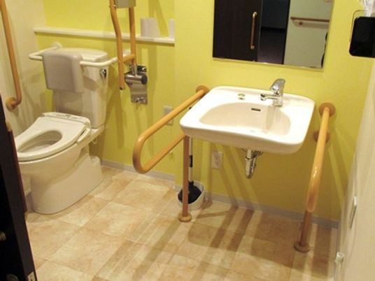施設の写真 トイレは壁と便座に手すりが完備されている。足腰が不自由な方でも安心して利用することができる。扉は引き戸タイプ。