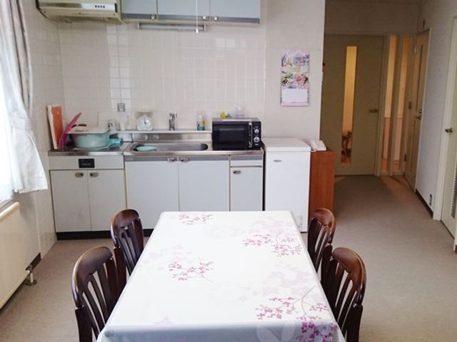 食卓とキッチンのある部屋 ダイニングルーム   テーブルを囲んで過ごせる明るい共有スペースです。奥には流し台や収納があり、食事準備もしやすそうです。