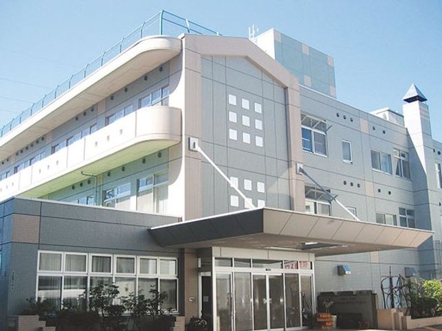 施設外観 外観   青空の下に建つ、明るい色合いの建物です。広いひさしのある出入口があり、来訪時の動線が分かりやすそうです。
