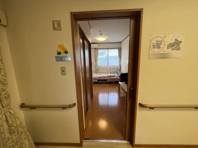 安心の居室入口 居室 手すりが設置された居室の入口です。暖かみのある照明と落ち着いた雰囲気が感じられます。