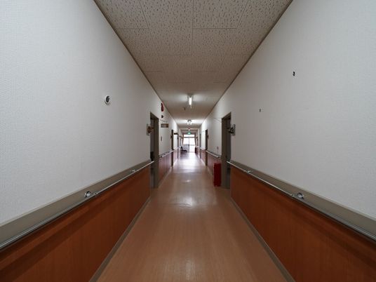 廊下の両側の壁に手すりが取りつけられている。消火器が２個置かれており、廊下の端にはベンチも置かれている。