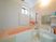 壁や浴槽が淡いオレンジ色と白色の明るい浴室で、壁には手すりが設置されている。鏡や小物置き場も備わっている。