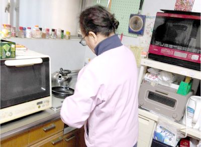 調理中の女性とキッチン