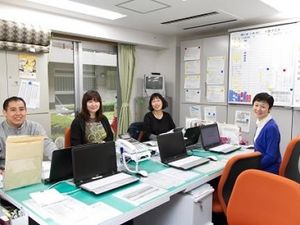 スタッフが並ぶ事務室  