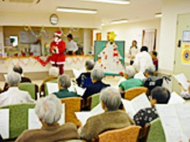 イベントが開催される共有スペース 行事 座っている方々が集まる温かな雰囲気の空間です。クリスマスを彩る飾りや衣装を身にまとったスタッフが、楽しい時間を提供しています。