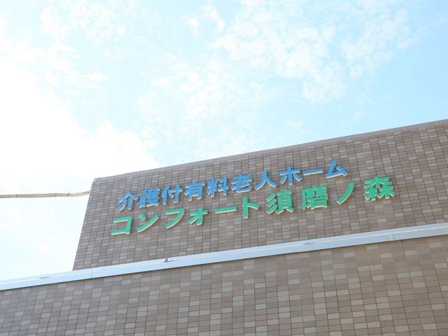 看板のある施設正面 外観 空に向かって掲げられた緑色の看板を備えた建物は、訪れる方々へ明確な案内を提供しています。