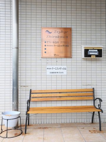 看板とベンチのエントランス 玄関 エレガントな看板が迎える入口には、休憩可能なベンチも完備され、訪れる方々にとって心地よい初めの一歩を提供します。