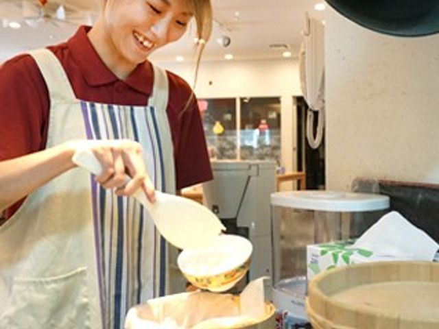 スタッフイメージ スタッフイメージ 笑顔のスタッフが料理を準備しています。施設での仕事を考える際、温かい雰囲気が感じられます。