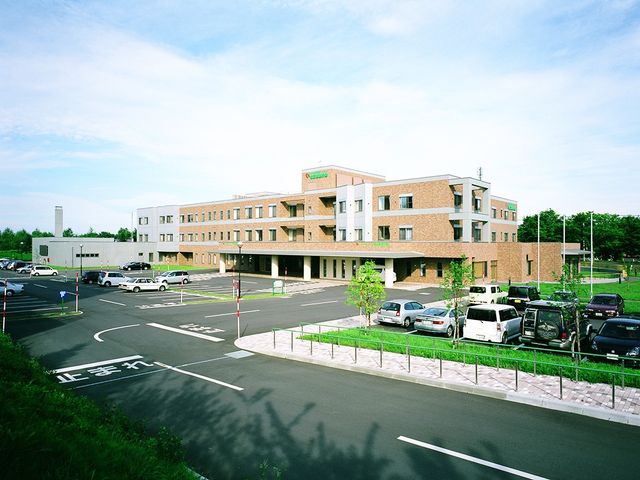 広い駐車場の建物外観 外観   明るい空の下に建つ、落ち着いた色合いの建物です。駐車場も広く、来訪しやすそうな印象です。