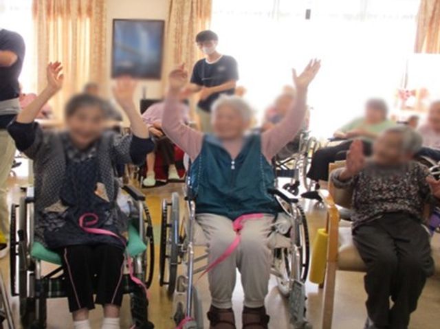 楽しそうな様子の居室 居室 車椅子の方々が楽しく手を挙げる様子が見られ、明るい雰囲気の空間です。