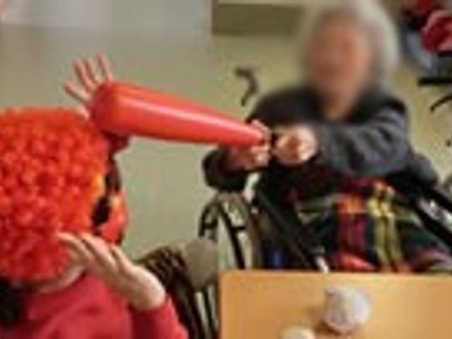 リビングアクティビティ リビング 楽しげなリビングで、介護スタッフと居住者が一緒に笑顔で交流を楽しんでいます。日常を感じられる良い空間です。