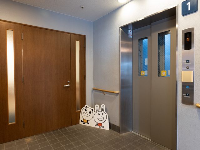 廊下のエレベーターとドア エレベーター 清潔感のあふれるエレベーター周辺の様子です。移動のしやすさを考慮した設計になっており、心地よい勤務環境を提供します。