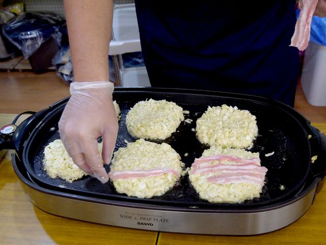 調理中のキッチン キッチン スタッフがグループでのお好み焼きを手際よく準備しています。暖かい雰囲気が漂う調理風景です。